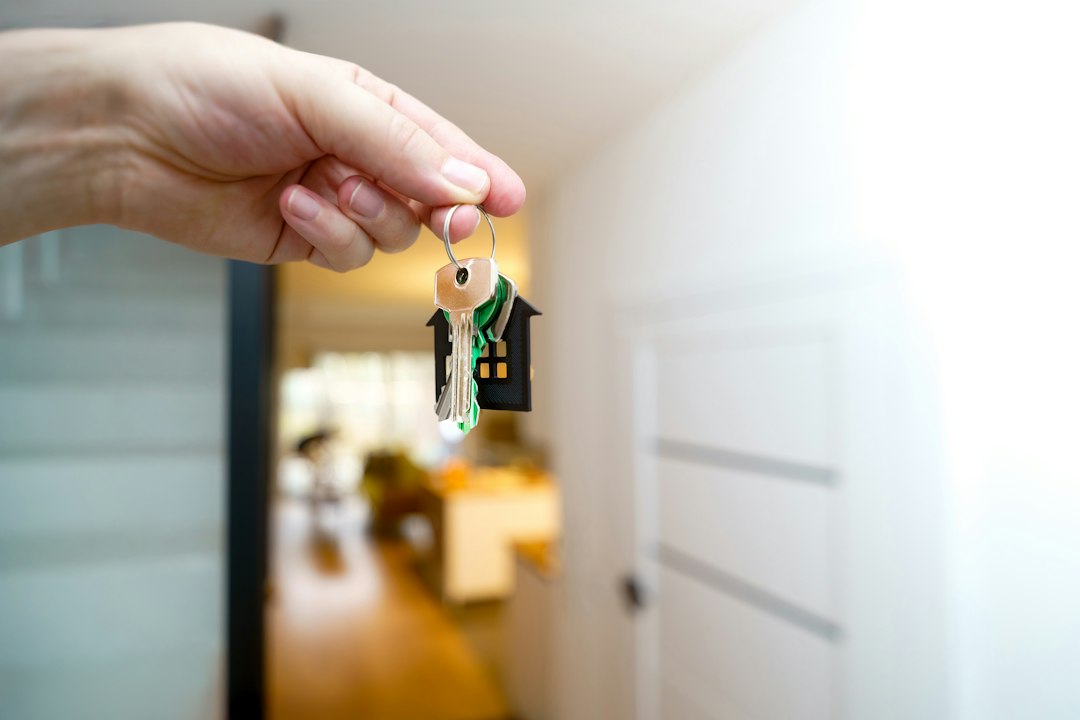 Hand holding a house key at a front door, representing landlord access