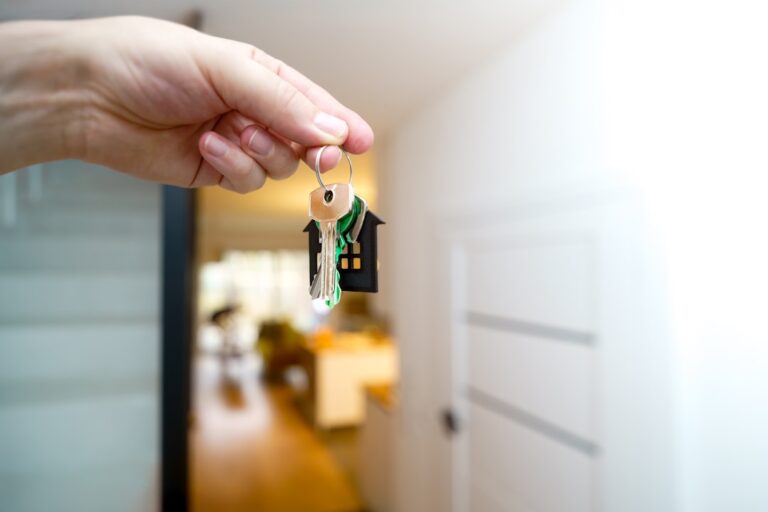 Hand holding house keys at a home, representing property transfer during probate