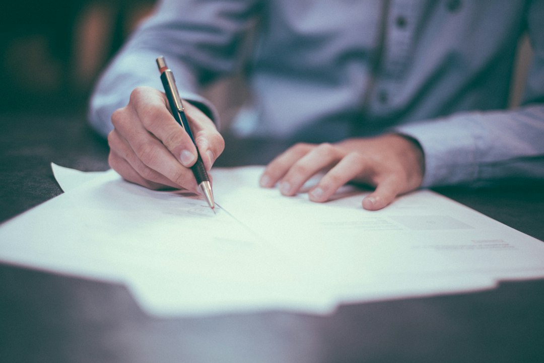 Close-up of a person signing real estate disclosure paperwork